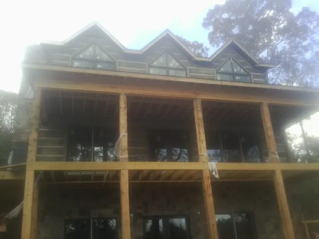 Dormers and porch framing on a large log home under construction — Roof Coating work by our crew in Belleville